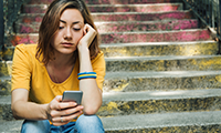 Teen girl dressed in yellow t-shirt breaking up with his boyfriend through messages. Dark toning.