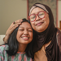A portrait of happy Asian Muslim young girl with mother and grandmother sitting at home during Hari Raya celebration