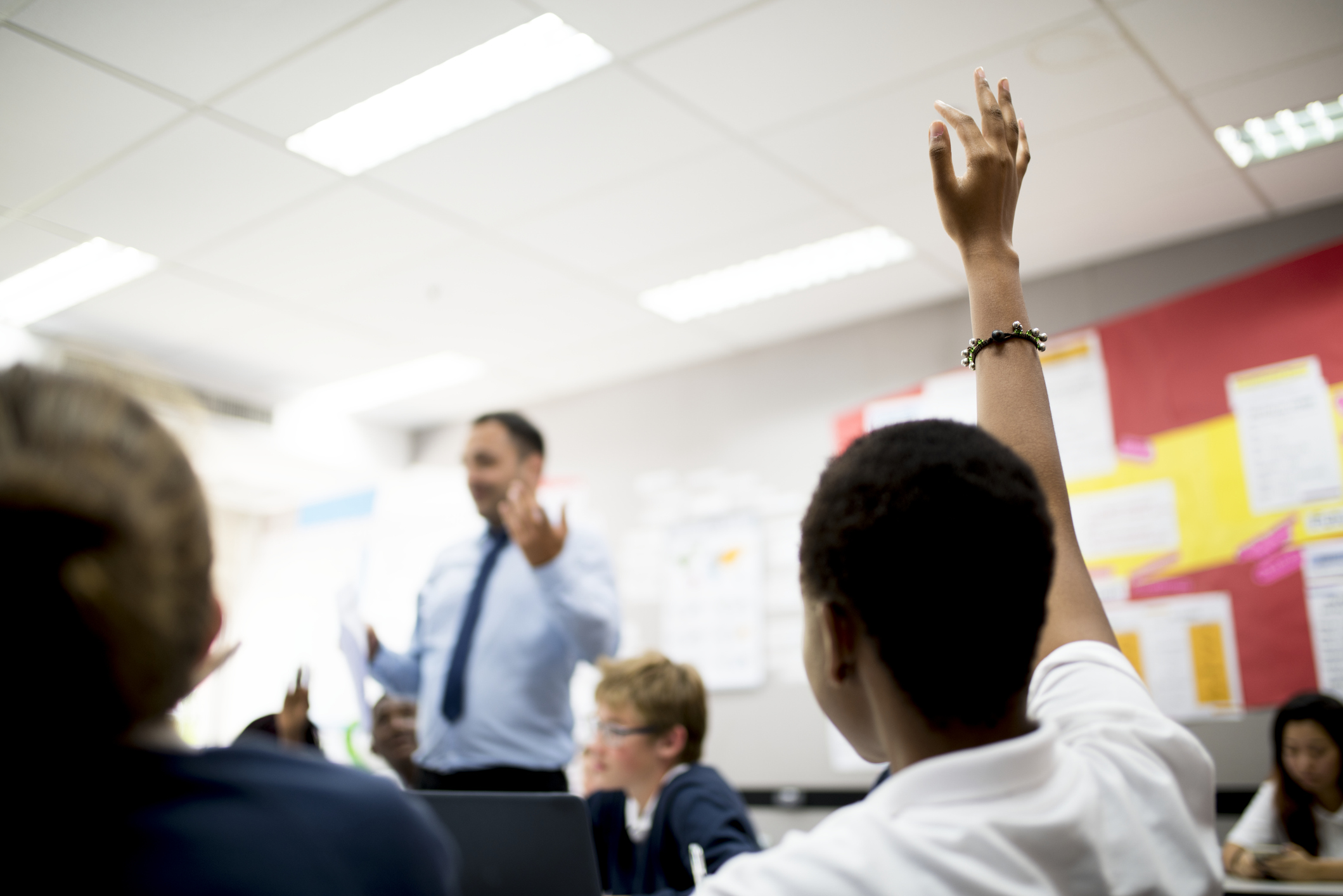 Student with her hand up in responding to the teacher.