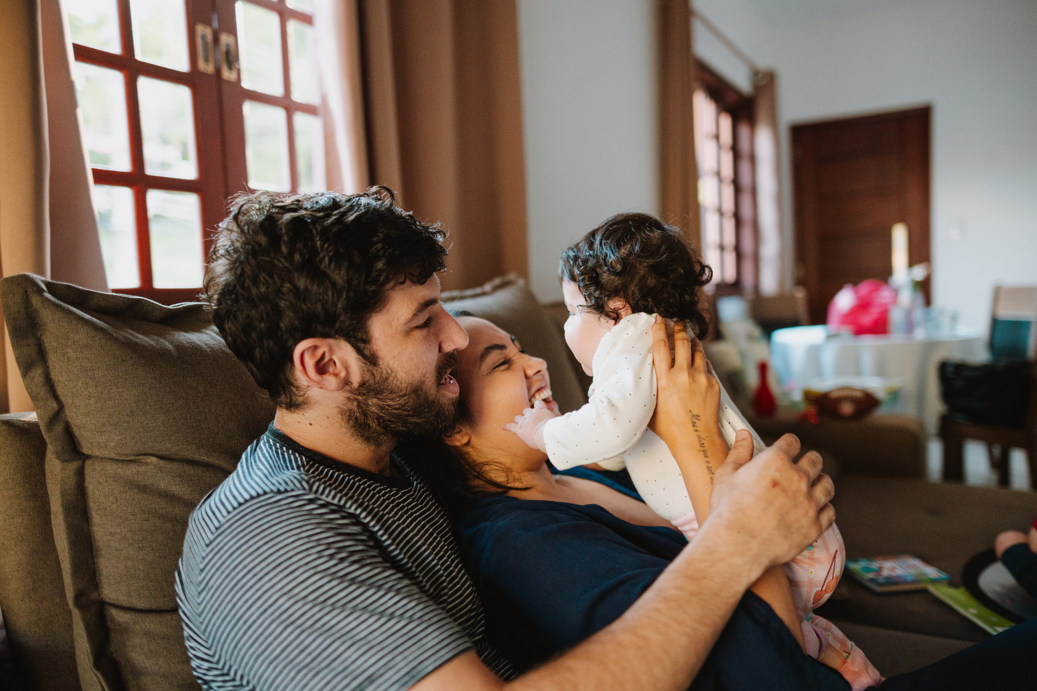 Father playing with toddler on the sofa
