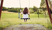 A young girl sitting on a swing