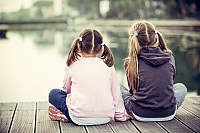 Two young sisters sitting on a dock