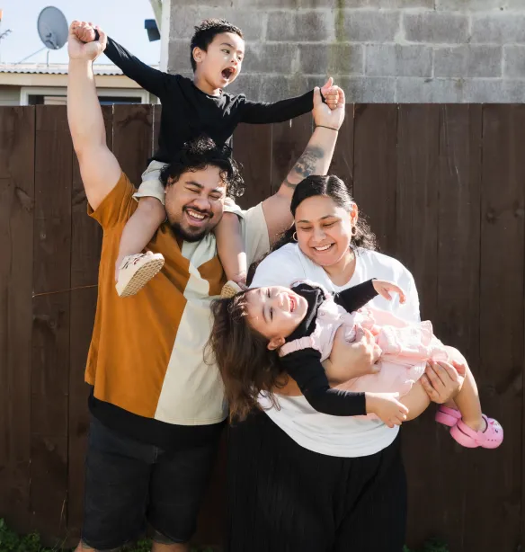 Pacific Islander Maori family of four smiling and enjoying together standing against brown background