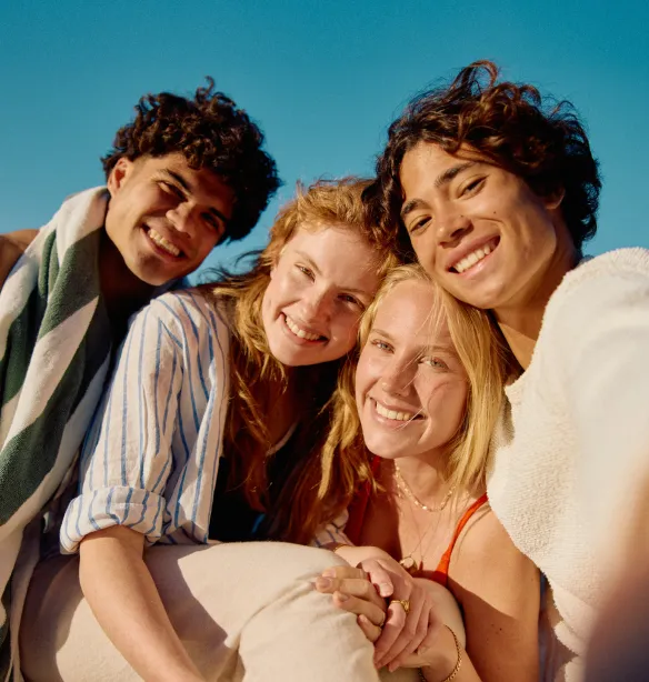 Young man holding phone and taking photo of himself with three friends