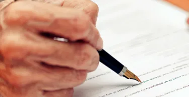 Close up of a senior person filling in a paper form