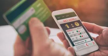 Cropped close up of hands betting on sports with smartphone