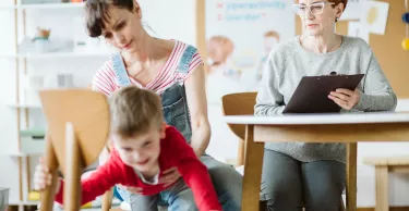 Young mom holding boy with adhd during session with psychotherapist