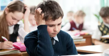 Schoolboy sitting at the classroom and working hardly