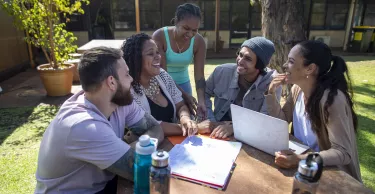 Young aboriginal students sitting together and studying outdoors in the sun in Australia