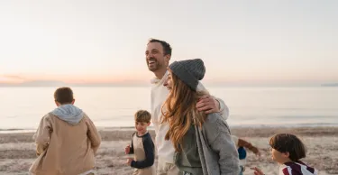 Photo of a young family, having a relaxed walk down the beach by the ocean Photo of a young family, having a relaxed walk down the beach by the ocean