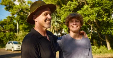 Father and teenage son smiling and embracing in a moment of affection.