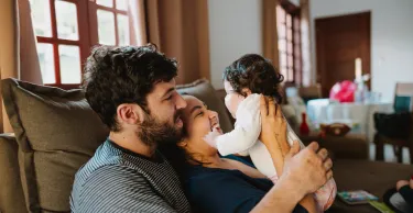 Father playing with toddler on the sofa