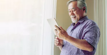 Senior man reading on this tablet at home