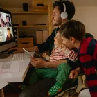 Photo of a man working from home, with his sons keeping him company, having a video conference call