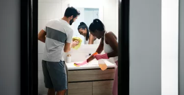 Multi-ethnic couple doing chores cleaning home bathroom