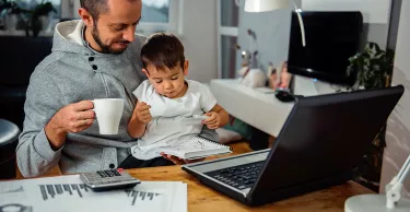 Father working from home with his son on his lap