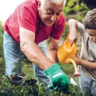 Grandfather and grandson playing in backyard with gardening tools