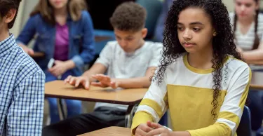 Teen girl sitting in a classroom looking pensive