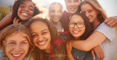 Teenage school friends smiling to camera, close up