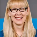 Woman with long blonde hair and dark rimmed glasses