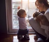 Young mother enjoying with her son and puppy in the late evening.