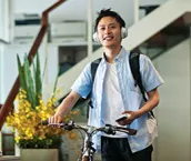 Man with headphones pushing bike