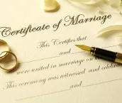 Closeup of a Certificate of Marriage, pen and wedding rings.