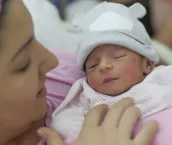 A newborn baby enters the world and mother holding newborn baby girl in the hospital.