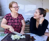 Happy mother and daughter talk while cooking in a rustic kitchen