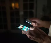 Close-up on a person betting online at home on their cell phone using their credit card.