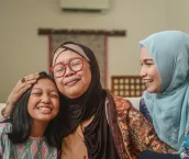 A portrait of happy Asian Muslim young girl with mother and grandmother sitting at home during Hari Raya celebration
