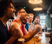 Happy young people watching game on TV in the bar