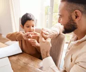 Learning, education and father with kid for sign language in home for homeschool. Development care, growth and deaf boy with hearing disability, bonding and happy man teaching him asl hand gestures.