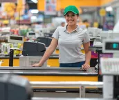 Beautiful young cashier facing camera smiling very happy ready to work