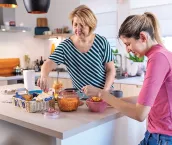 A young woman with hearing aids talking to her mother in the kitchen. They have a breakfast and enjoying the time they spending together. A young woman with hearing aids talking to her mother in the kitchen. They have a breakfast and enjoying the time they spending together.