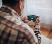 Elderly man uses smartphone for sports betting from home Elderly man uses smartphone for sports betting from home