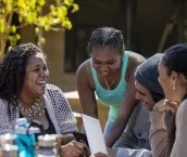Young aboriginal students studying together outdoors in the sun in Australia.