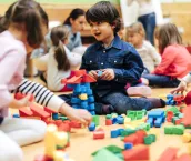 Group of children playing with blocks in kindergarten. Showing their imagination and skill and creativity. Selective focus to little boy building with blocks.