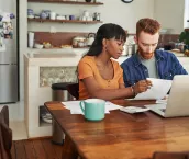 A couple reviewing paperwork and looking through the laptop on the kitchen table