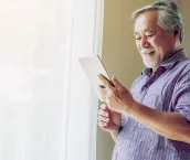 Senior man reading on this tablet at home