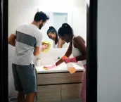 Multi-ethnic couple doing chores cleaning home bathroom