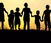 Silhouette, group of happy children playing on meadow, sunset, summertime