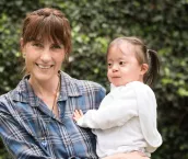 Mature woman carrying her little girl with down syndrome