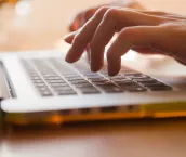 Close up of a woman tying on a laptop