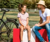 Smiling father sitting with teenage daughter in park Smiling father sitting with teenage daughter in park