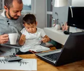 Father working from home with his son on his lap