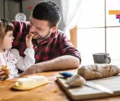 Toddler feeding bread to her father as they have breakfast