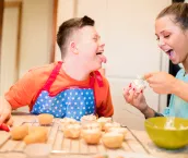A boy with down syndrome bakes cakes with his sister in the kitchen.