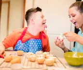 A boy with down syndrome bakes cakes with his sister in the kitchen. A boy with down syndrome bakes cakes with his sister in the kitchen.