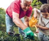 Grandfather and grandson playing in backyard with gardening tools